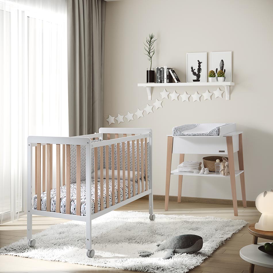 Micuna Nordika Berço 120x60 em branco e madeira, com colchão estampado, num quarto de bebé moderno com trocador a condizer.