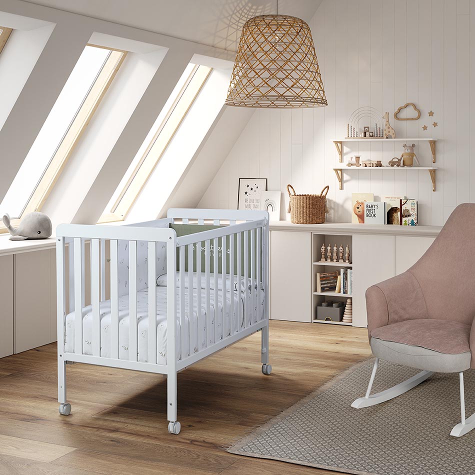 Micuna Nordika Berço 120x60 totalmente branco, com colchão estampado, num quarto de bebé luminoso com teto inclinado e decoração minimalista.