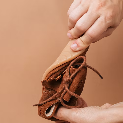 Mãos a demonstrar a extrema flexibilidade da sola das sapatilhas Rooties Carneiras Mémé Camel.