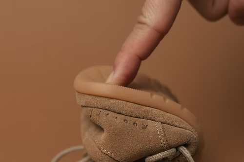 Dedo a pressionar a sola de uma carneira Rooties Mémé Areia para demonstrar a sua extrema flexibilidade e design barefoot.