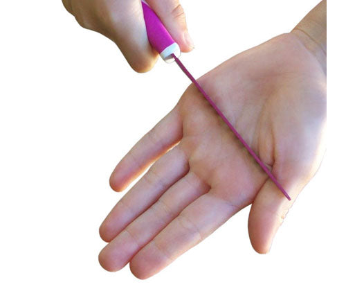 Demonstração de segurança: uma ponta de faca KiddiKutter (rosa) desliza inofensivamente sobre a palma de uma mão adulta, ilustrando a lâmina não afiada.