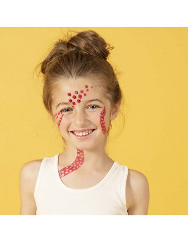 Menina sorridente com padrões de pontos vermelhos criativos no rosto e pescoço usando marcadores de tatuagem.