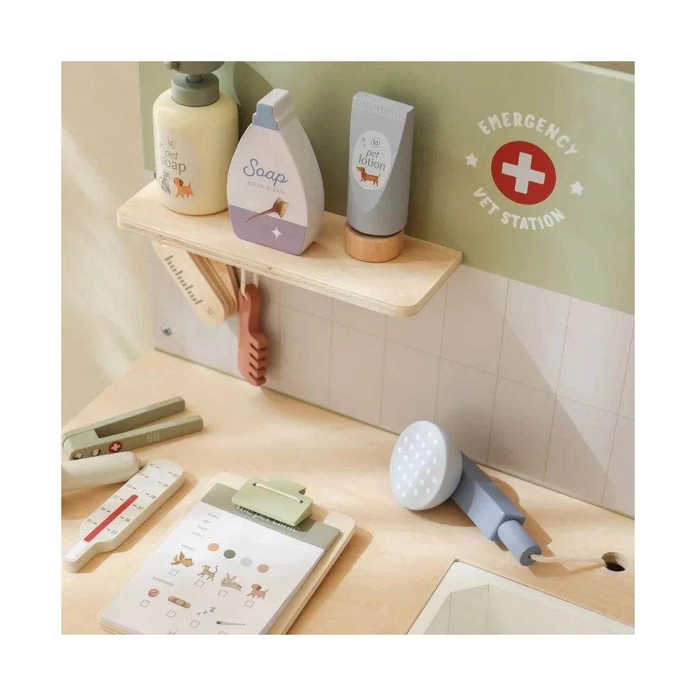 Detalhe da bancada da clínica veterinária mostrando o lavatório, o chuveiro de mão, o termómetro e os frascos de sabão e loção na prateleira superior.