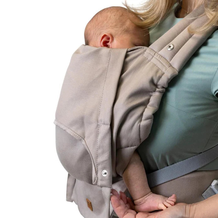 Detalhe de um bebé a dormir profundamente dentro da mochila Isara ELITE bege, mostrando o acolchoamento e o fecho de pressão lateral.
