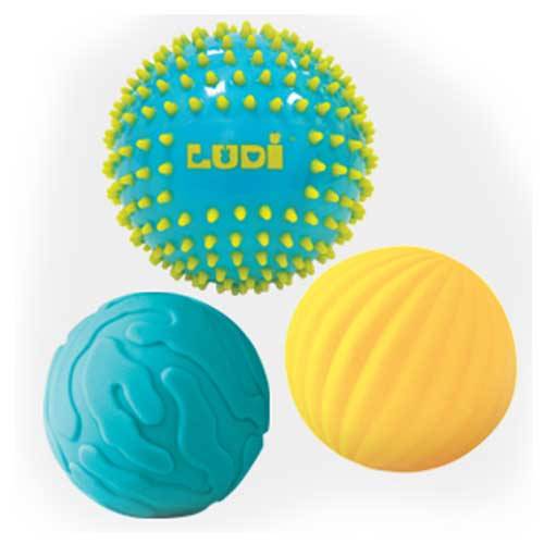 Três bolas sensoriais Ludi isoladas, uma azul com espinhos, uma azul texturada e uma amarela com nervuras.
