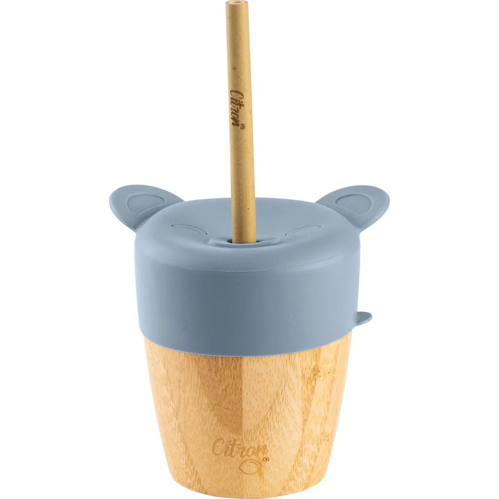 Detalhe de um copo de bambu Citron com tampa de silicone azul acinzentada em forma de urso, com palhinha de bambu inserida.