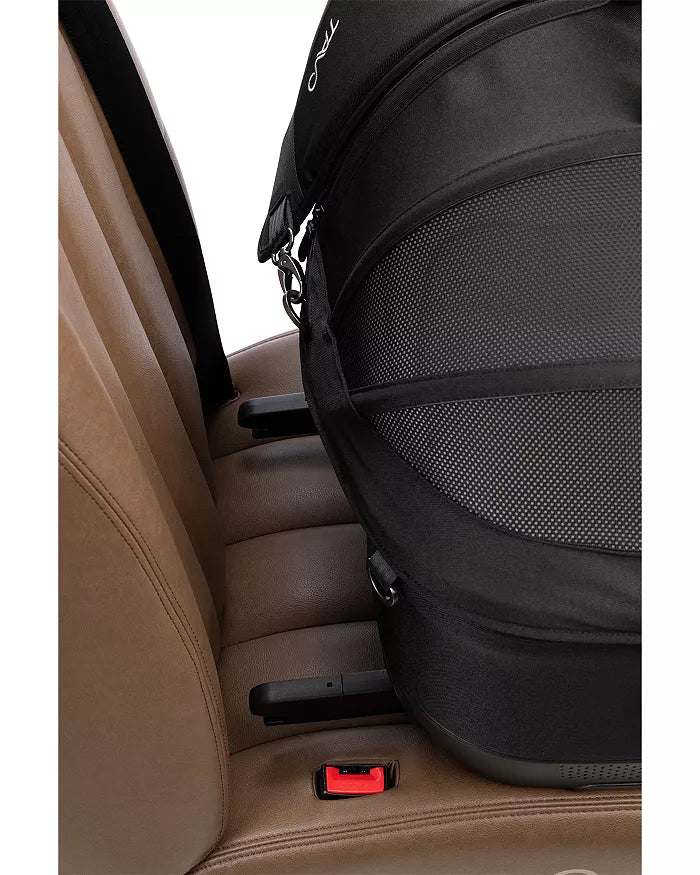 Detalhe da instalação do transportador TAVO MAEVE no banco do carro, mostrando o encaixe ISOFIX no assento de pele castanha.