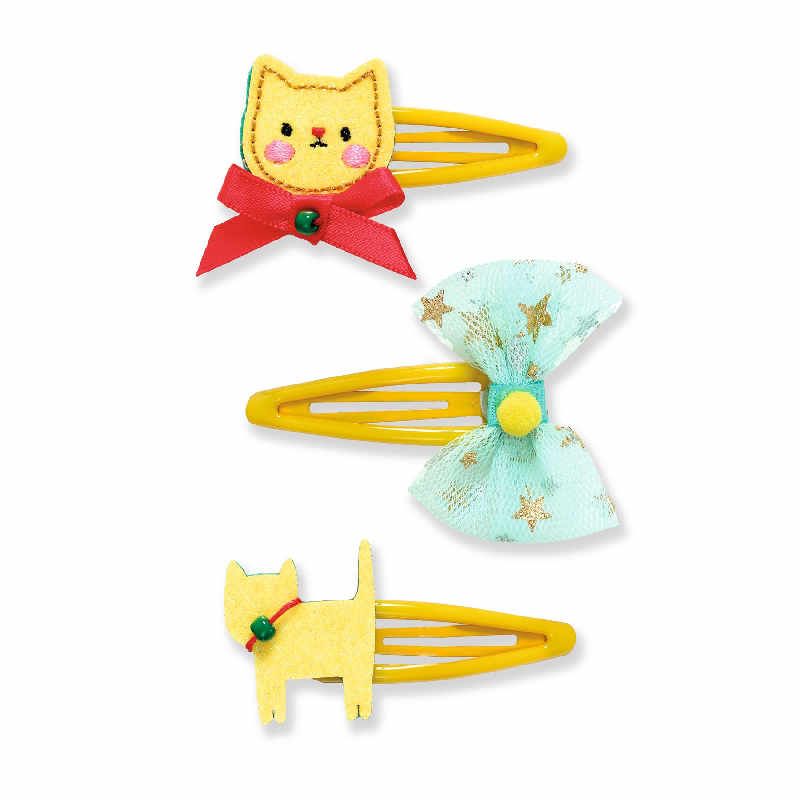 Conjunto de três barrettes amarelas para cabelo, decoradas com um gato bordado, um laço de tule azul e um gato em pé, todas da marca Djeco.