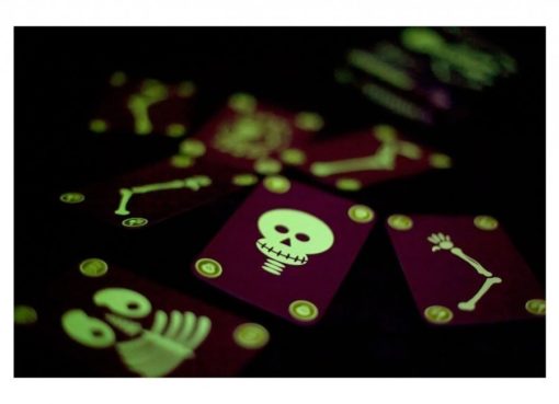 Cartas do jogo Djeco Bogoss a brilhar no escuro, mostrando o efeito fluorescente dos esqueletos.