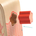 Detalhe de uma peça vermelha em forma de flor do Djeco Jogo de Encaixe de formas e cores a ser inserida no orifício lateral.