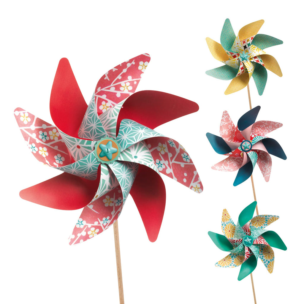 Quatro cata-ventos Djeco acabados, em destaque um grande vermelho e turquesa, e três mais pequenos com padrões florais e geométricos coloridos.