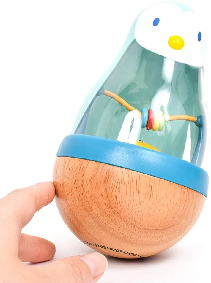 Detalhe do Djeco Roly Pingui a ser empurrado, mostrando a sua base arredondada que permite balançar sem cair.