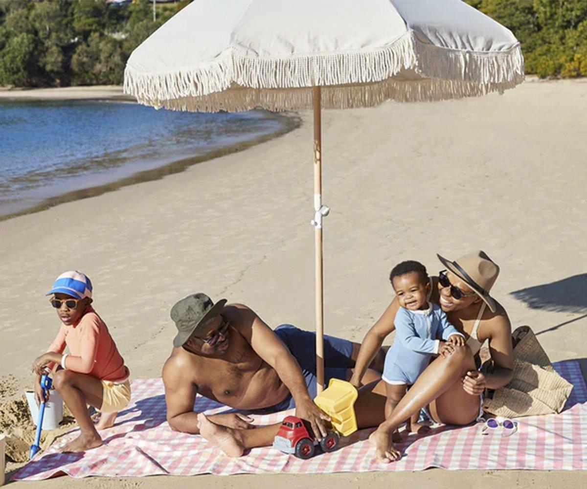 A manta de praia XL Dock & Bay com várias pessoas sentadas confortavelmente, demonstrando a capacidade para 5 a 7 pessoas.