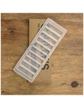 Tabuleiro de silicone Chilly's Ice Cube Tray, com 10 compartimentos, parcialmente sobre a sua embalagem de cartão, sobre fundo de madeira.