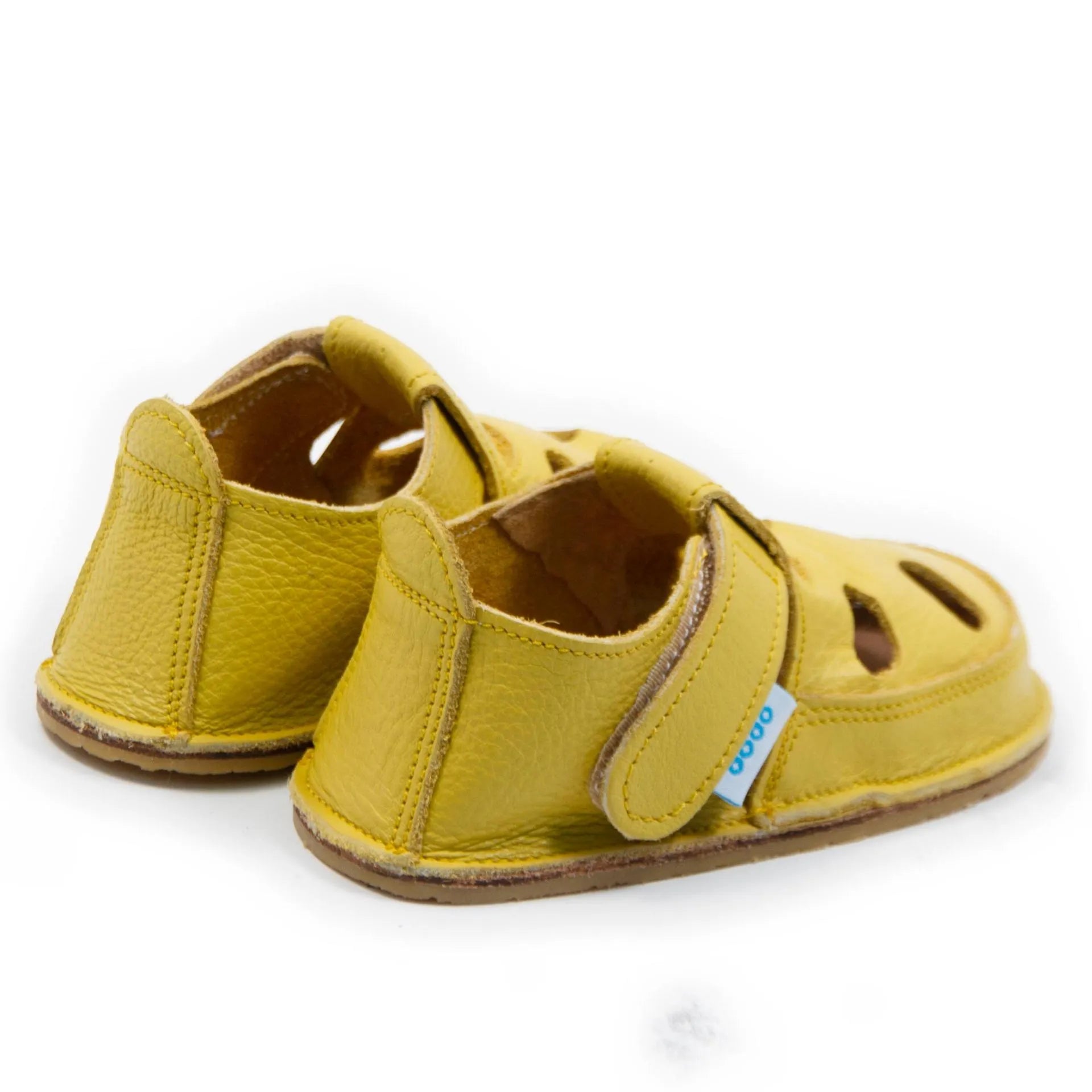  Vista lateral das sandálias barefoot Dodo Shoes em amarelo, com sistema de fecho em Velcro para um ajuste seguro e design anatómico que apoia o desenvolvimento natural dos pés.