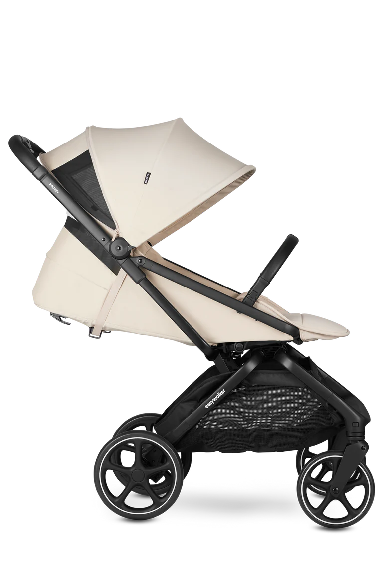 Vista lateral do carrinho Easywalker Rockey L bege, com capota parcialmente aberta revelando rede de ventilação, assento reclinado e cesto de arrumação grande.
