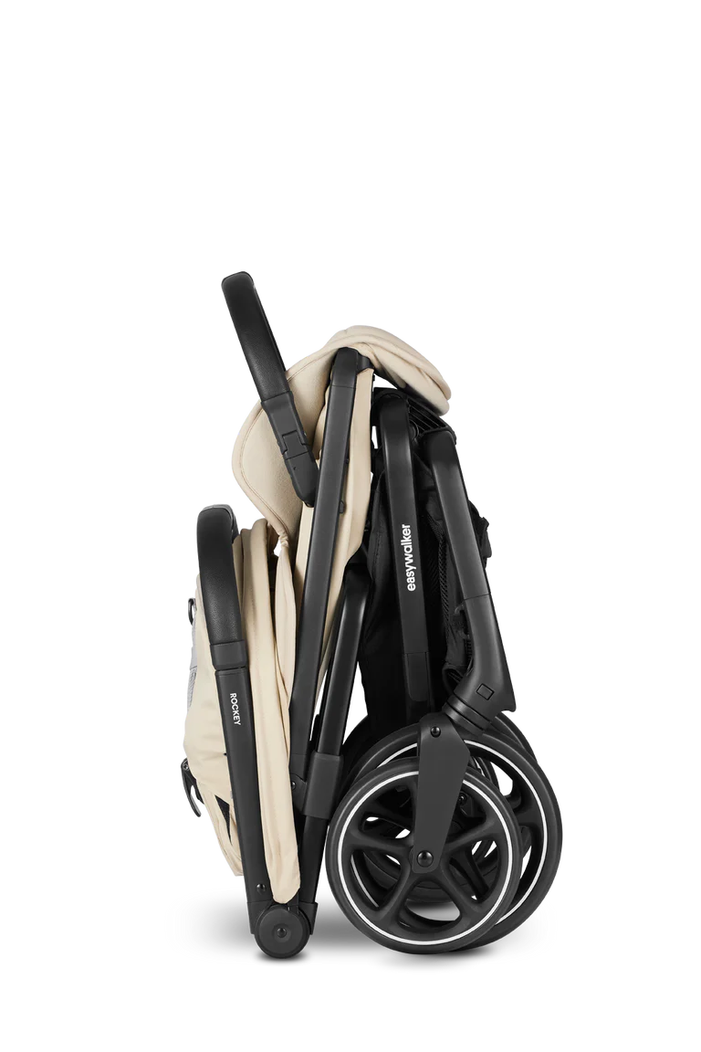 Carrinho Easywalker Rockey L cor bege dobrado de forma compacta, pronto para arrumação ou transporte, visto de lado.