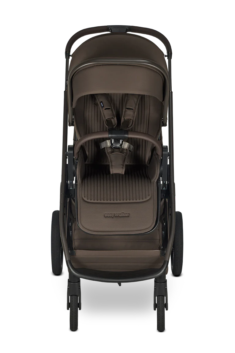 Vista frontal do carrinho Easywalker Zoey com assento em tecido canelado castanho-escuro, cinto de segurança visível e barra de apoio.