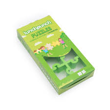 Embalagem de cartão verde com janela transparente mostrando o cortador de sanduíche Lunch Punch Puzzles no interior.