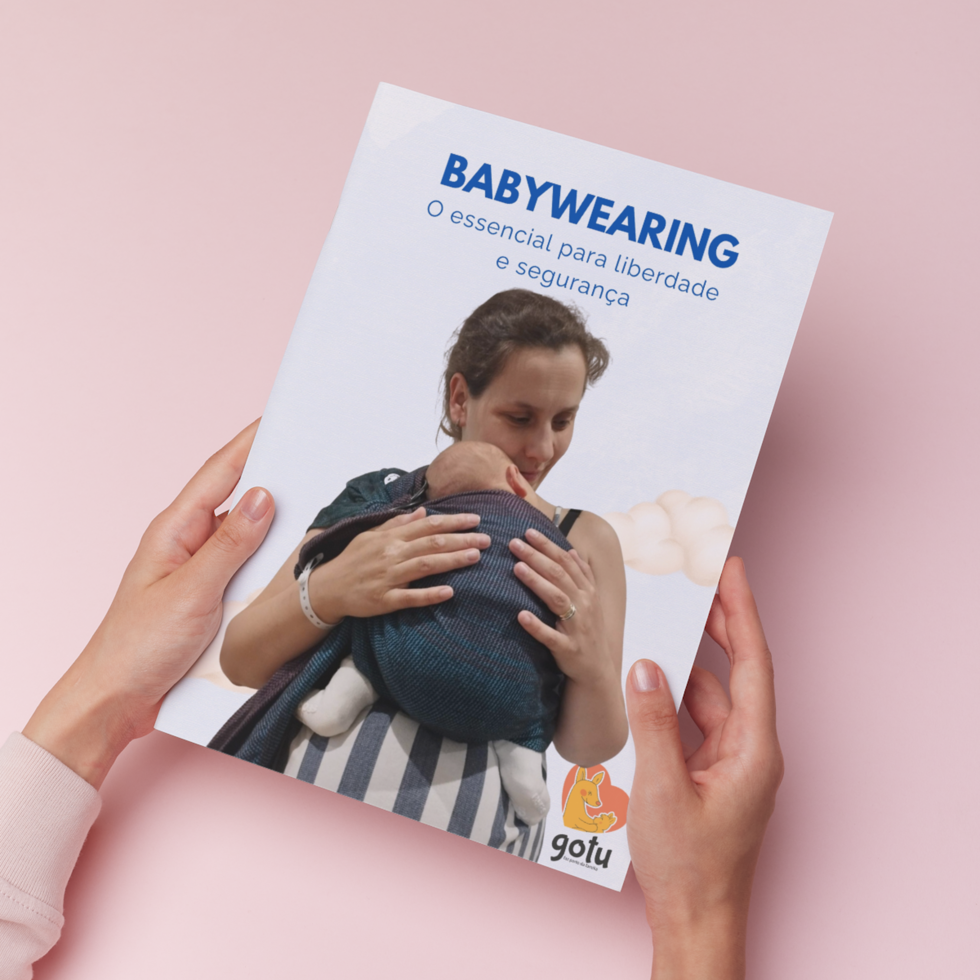 Mãos a segurar o folheto do evento "Babywearing: O essencial para liberdade e segurança" da Gotu, com uma mãe a abraçar o bebé.
