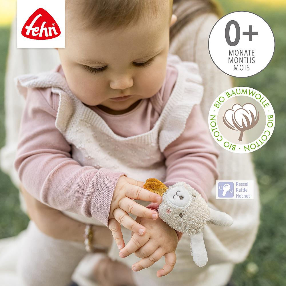 Bebé a explorar a pulseira de atividades Fehn com guizo coelho no pulso, estimulando a preensão e o tato, ideal para 0+ meses.