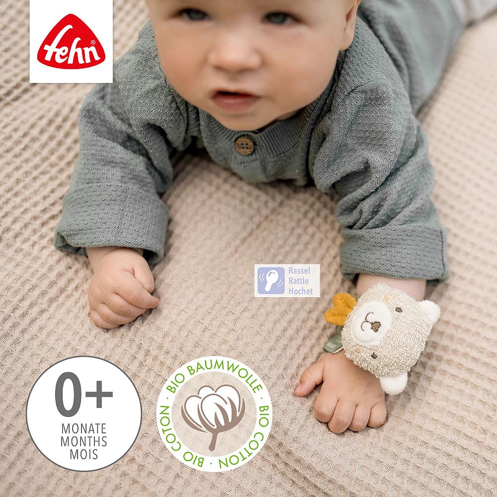 Bebé de 0+ meses a gatinhar, a usar a pulseira Fehn com guizo Urso no pulso, estimulando a preensão e audição.