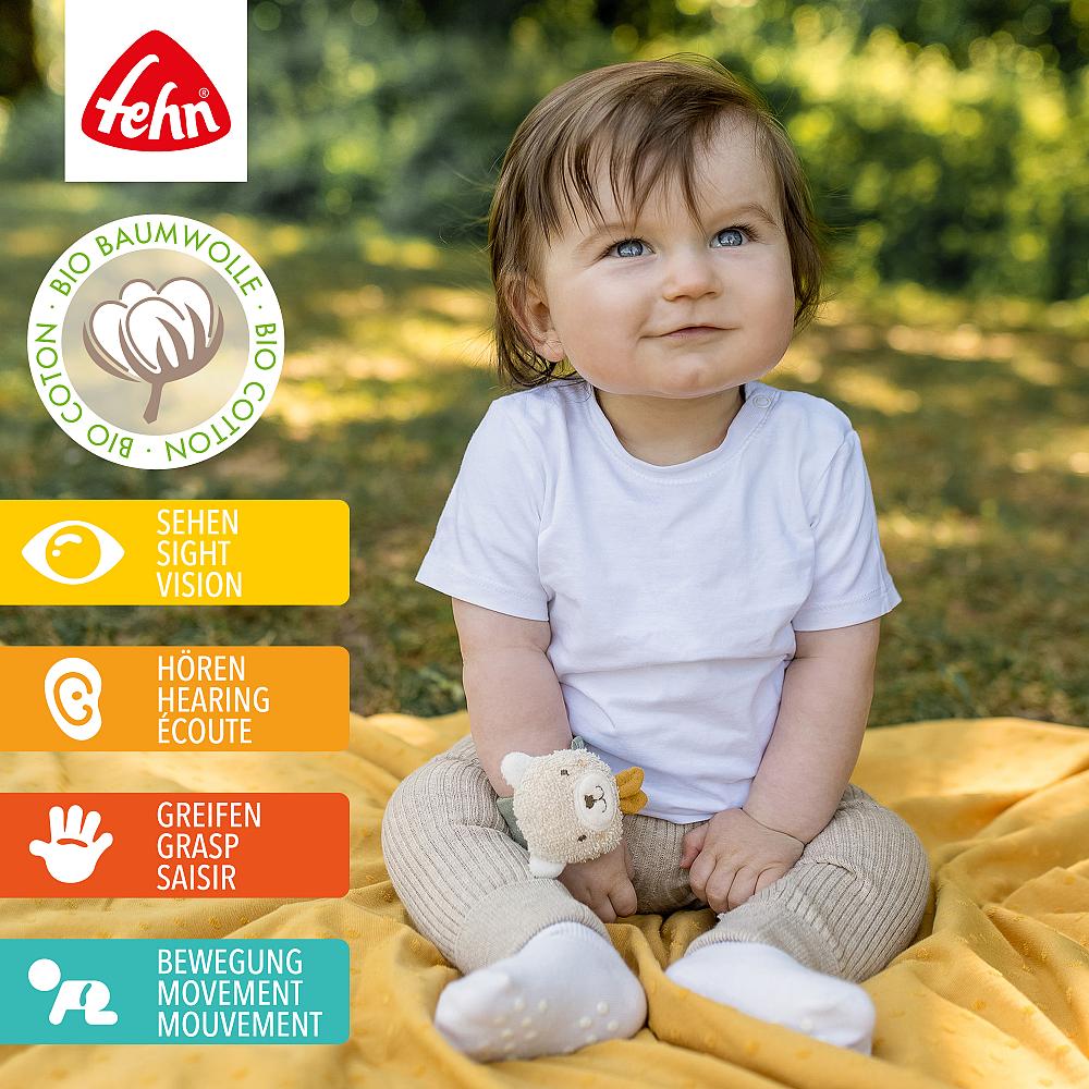 Bebé sorridente ao ar livre a usar a pulseira Fehn Urso, destacando os benefícios para a visão, audição, preensão e movimento.