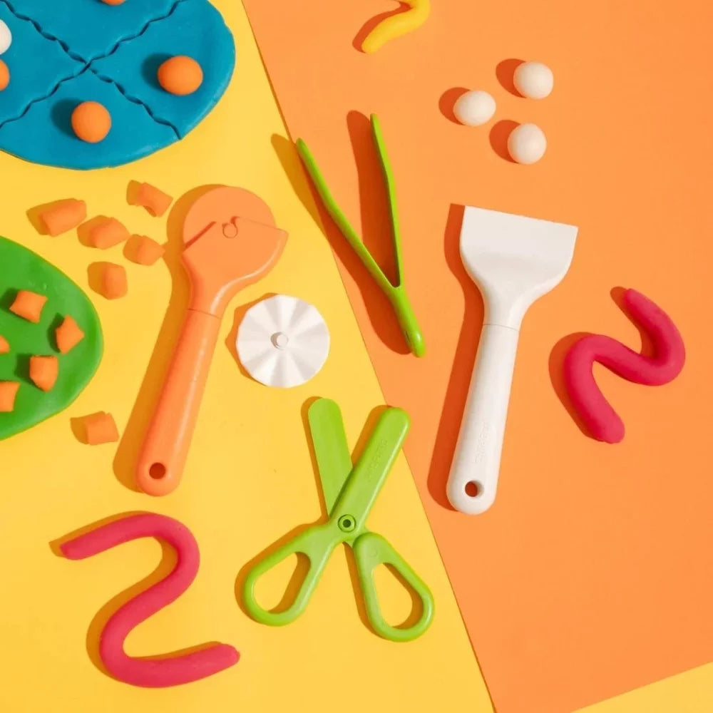 Vista aérea das cinco ferramentas ChildGen para plasticina dispostas sobre um fundo laranja e amarelo, incluindo plasticina colorida.