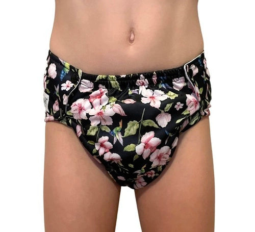 Criança a usar cueca absorvente reutilizável Pupus Hummingbirds com padrão floral de colibris e flores cor-de-rosa.