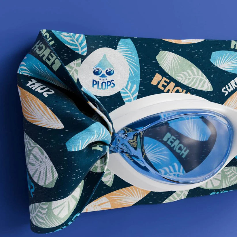 Detalhe dos Waterplops Óculos para Piscina Surf, mostrando a armação branca, lentes azuis, o logótipo na banda elástica e o padrão de pranchas de surf.