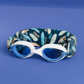 Waterplops Óculos para Piscina Surf de armação branca e lentes azuis, com a banda elástica de padrão de pranchas de surf dobrada atrás, sobre fundo azul.