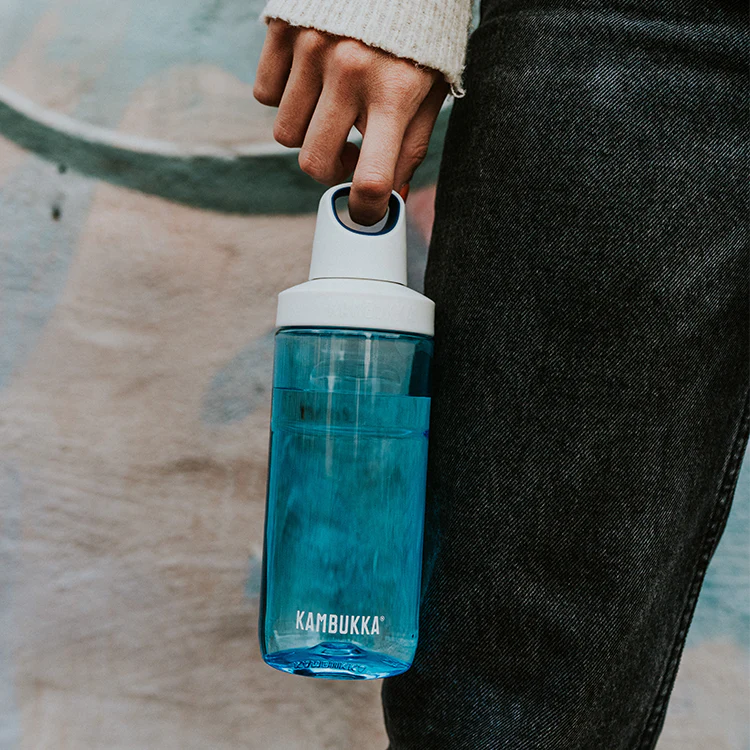 Close-up da garrafa Kambukka RENO Sapphire 500ml azul, sendo transportada pela pega, com foco na portabilidade e estilo.