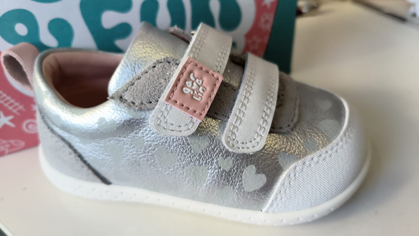 Sapatilha respeitadora Garvalín Plata prateada com corações, vista de lado, mostrando as duas tiras de velcro e a biqueira reforçada.