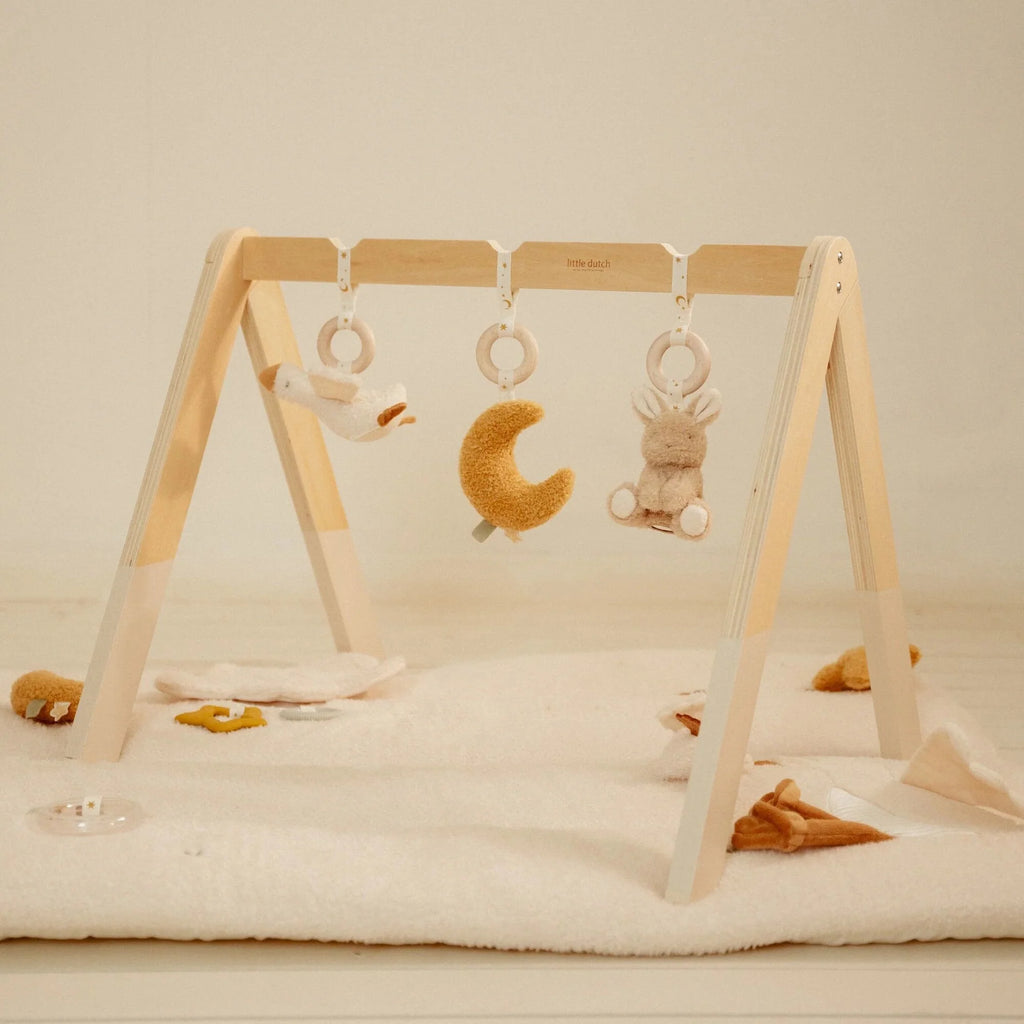 Ginásio de atividades Little Dutch em madeira clara com três brinquedos suspensos (pato, lua amarela e coelho) sobre um tapete branco.