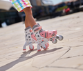 Criança a usar os patins Globber 2 em 1 rosa pastel em modo em linha sobre pavimento exterior.