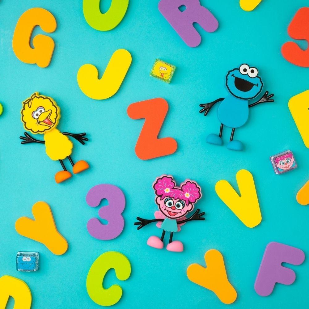 Vários bonecos GloPals da Rua Sésamo com letras e números coloridos, exibindo a coleção completa e o potencial educativo.