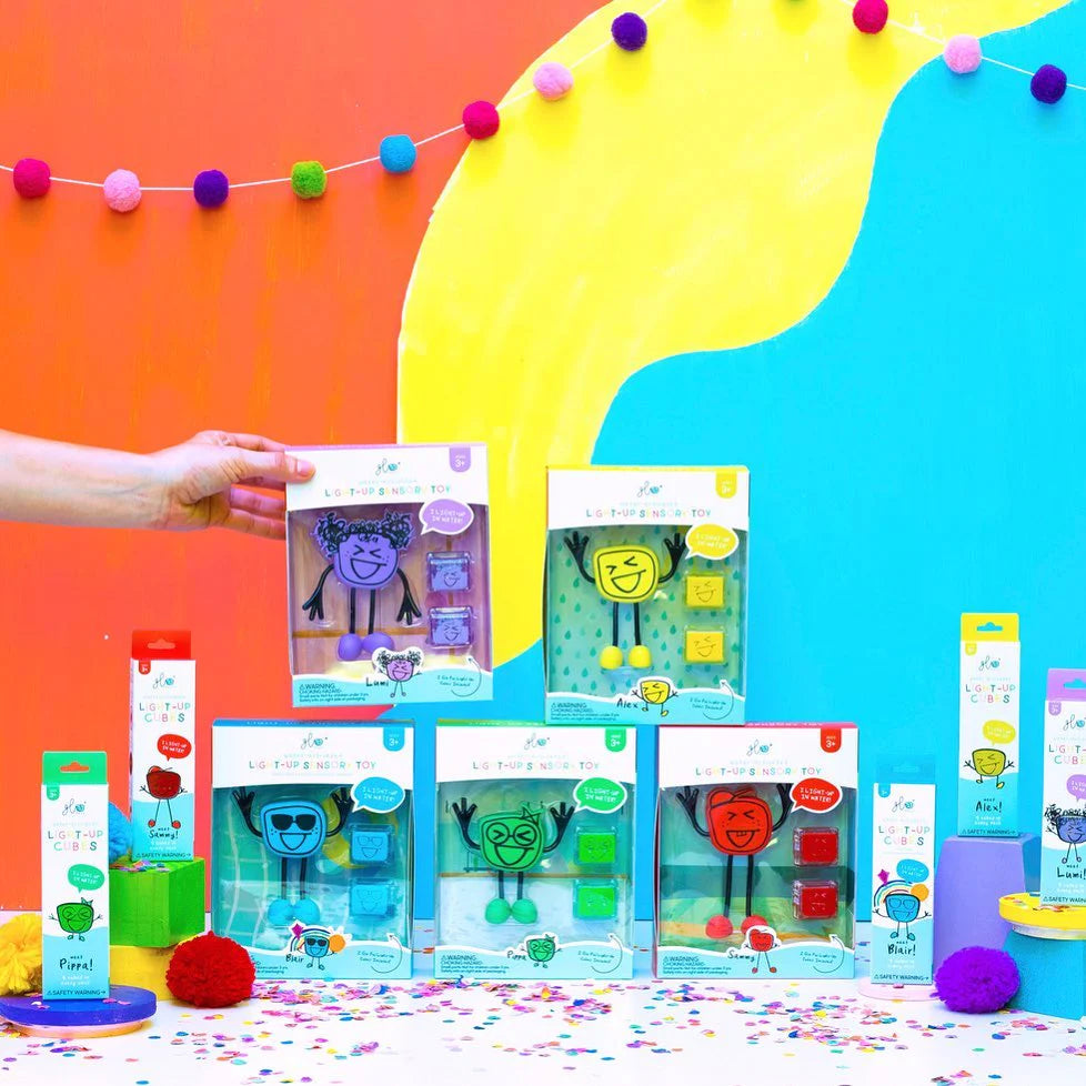 Conjunto GloPals com 5 bonecos e cubos luminosos em embalagens coloridas, exibidos com decoração festiva.
