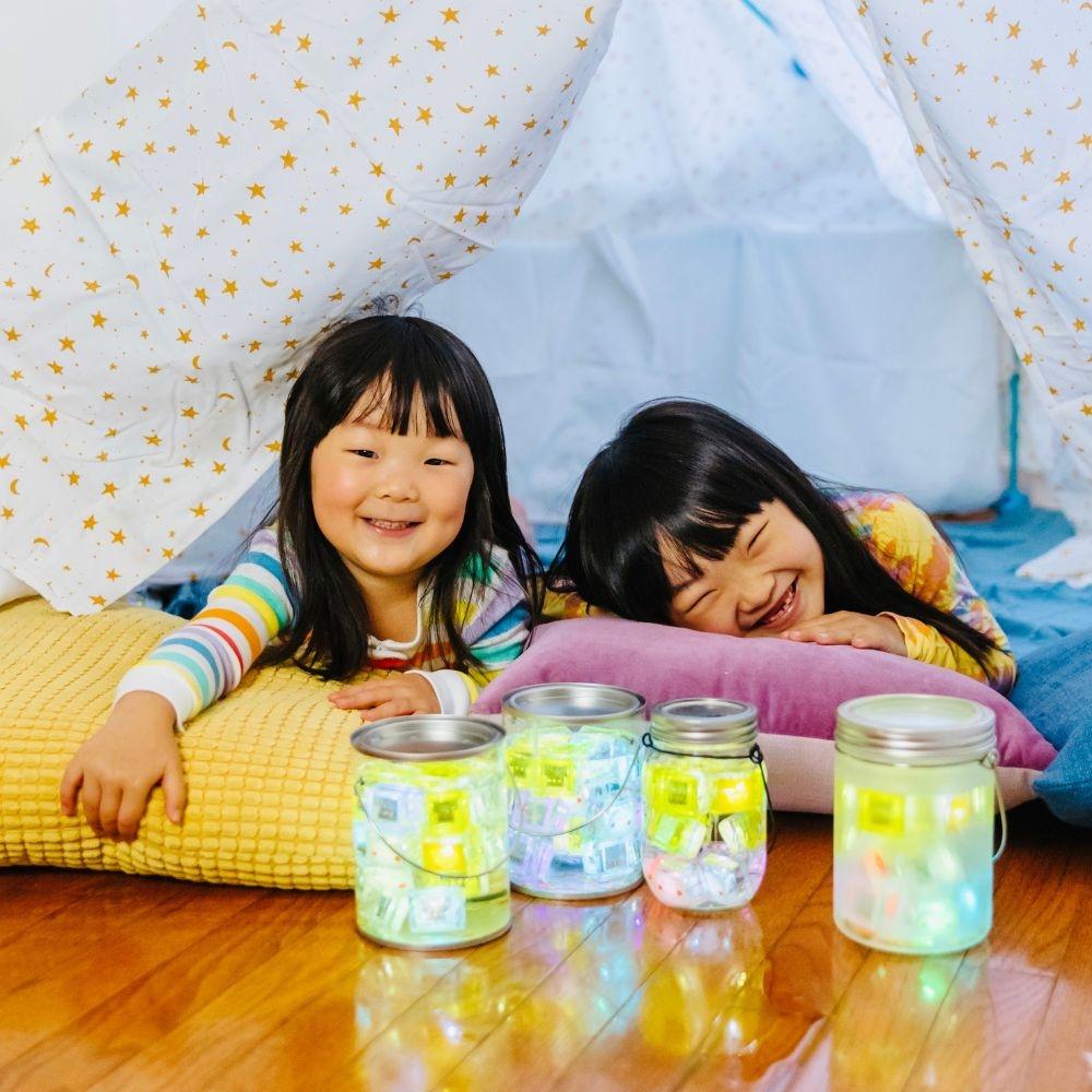 Criança a brincar com um cubo de luz GloPal na mão, demonstrando a interação sensorial e o tamanho do brinquedo.