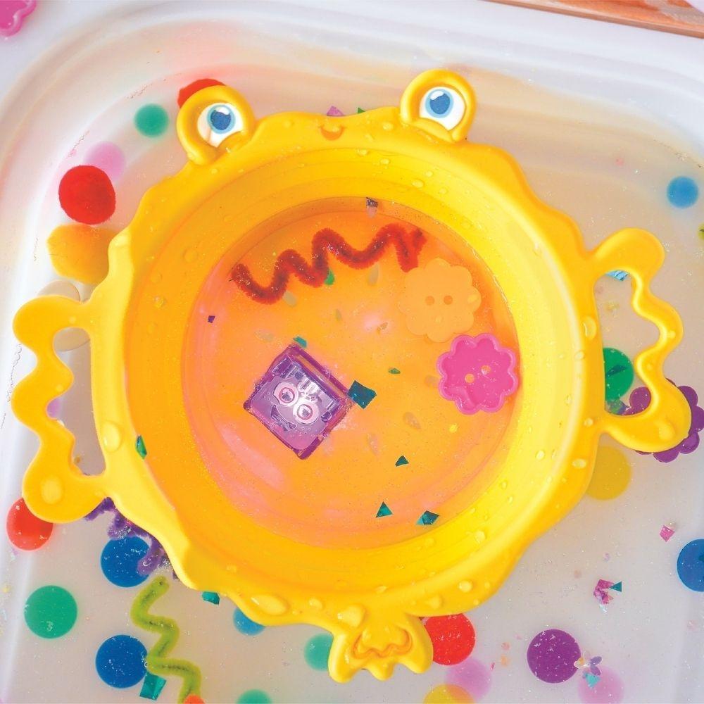 Ferramenta sensorial GloPals amarela em forma de peixe/caranguejo, cheia de água e confetes coloridos, ideal para brincadeiras aquáticas.