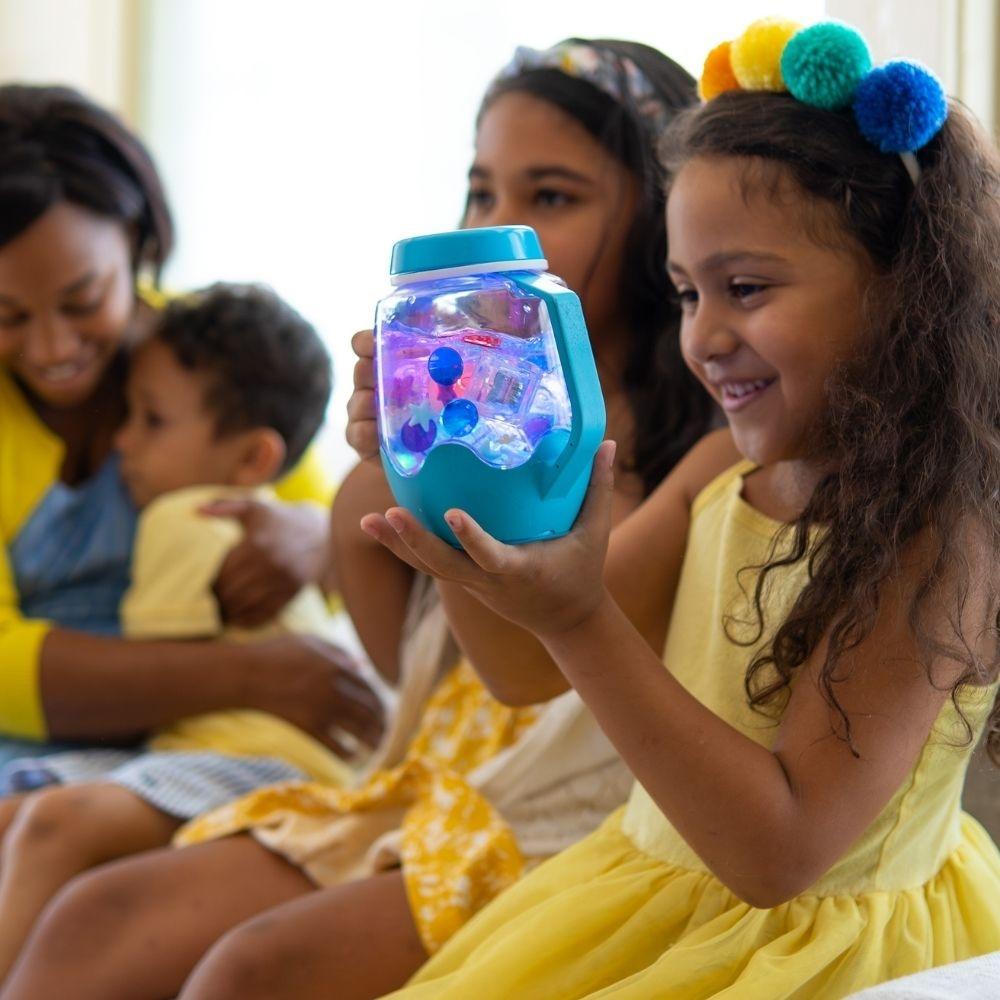 Família a partilhar um momento de brincadeira sensorial com o Jarro da Calma GloPals azul iluminado.