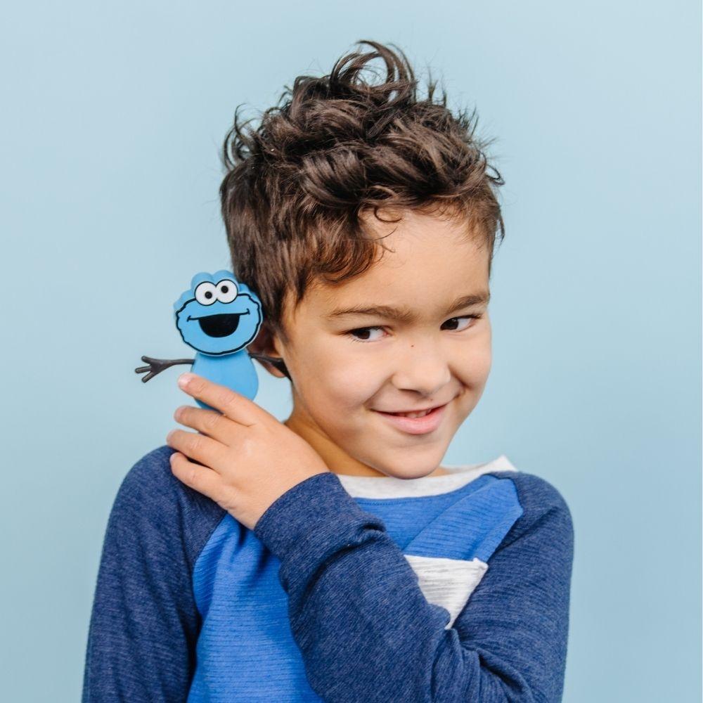 Criança sorrindo com o boneco Monstro das Bolachas GloPals no ombro, demonstrando o apelo do brinquedo para crianças.