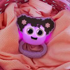 GloPals Mordedor & Guizo com luz Lilás, iluminado em roxo vibrante, pousado confortavelmente sobre um tecido texturizado cor-de-rosa.
