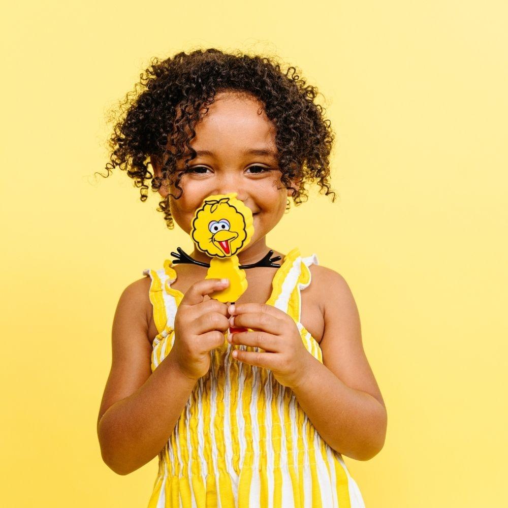 Criança feliz a segurar o boneco Poupas GloPals perto do rosto, sorrindo.