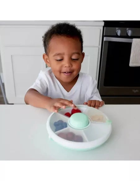 Criança feliz a interagir com uma lancheira GoBe Snack Spin de 21 cm cheia de fruta e bagas, numa cozinha moderna.