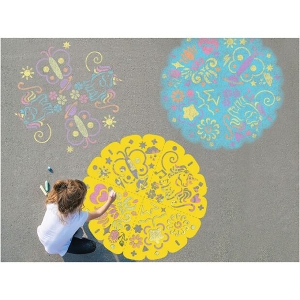 Criança a usar o estêncil amarelo para desenhar uma mandala colorida no chão, ao lado de outras duas mandalas já concluídas.