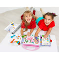 Duas crianças a sorrir e a colorir juntas no chão usando o Kit de colorir Haku Yoka O meu primeiro Kit de colorir Dinossauros.