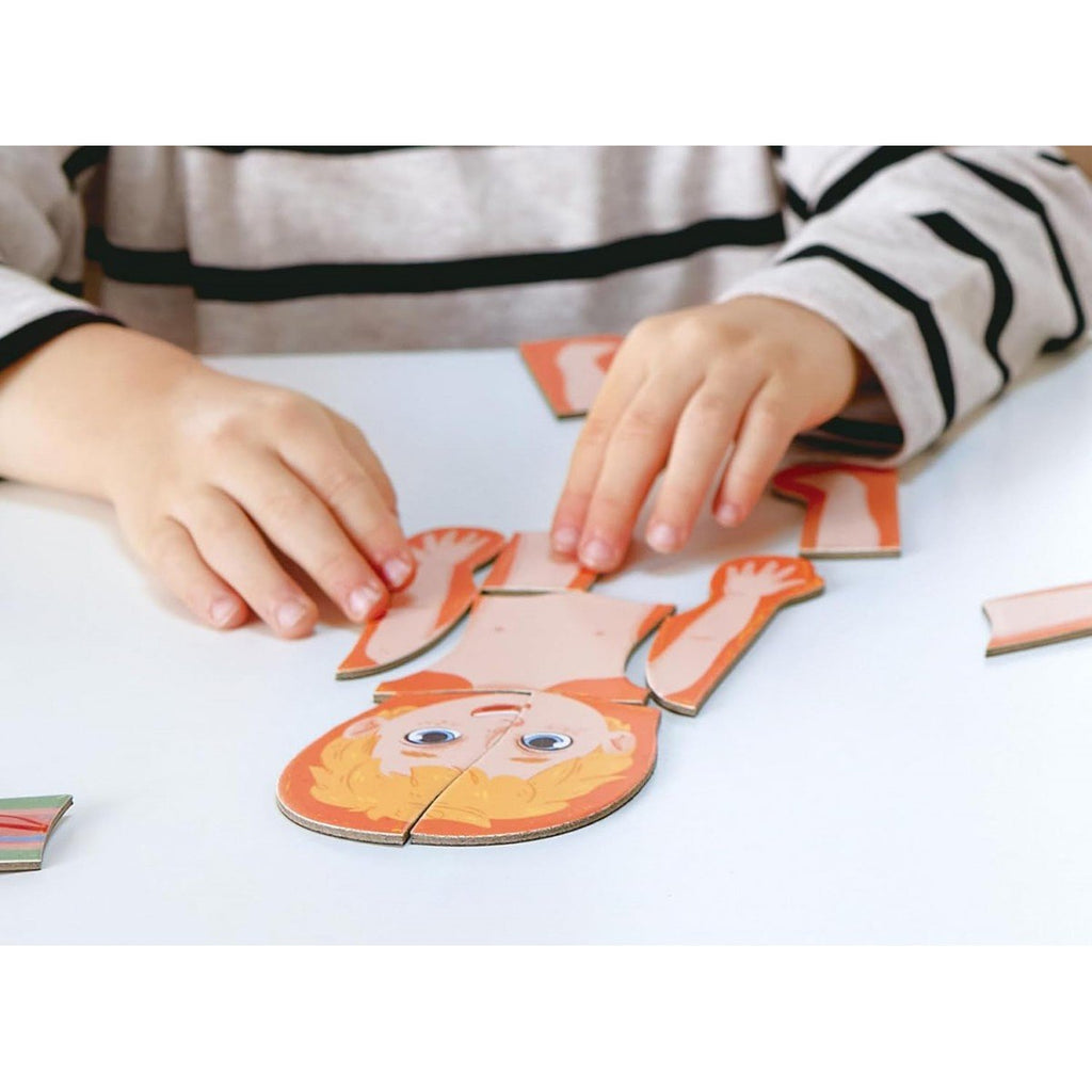 Criança a montar o Hape Puzzle Magnético Corpo Humano, focando-se na parte superior do corpo.