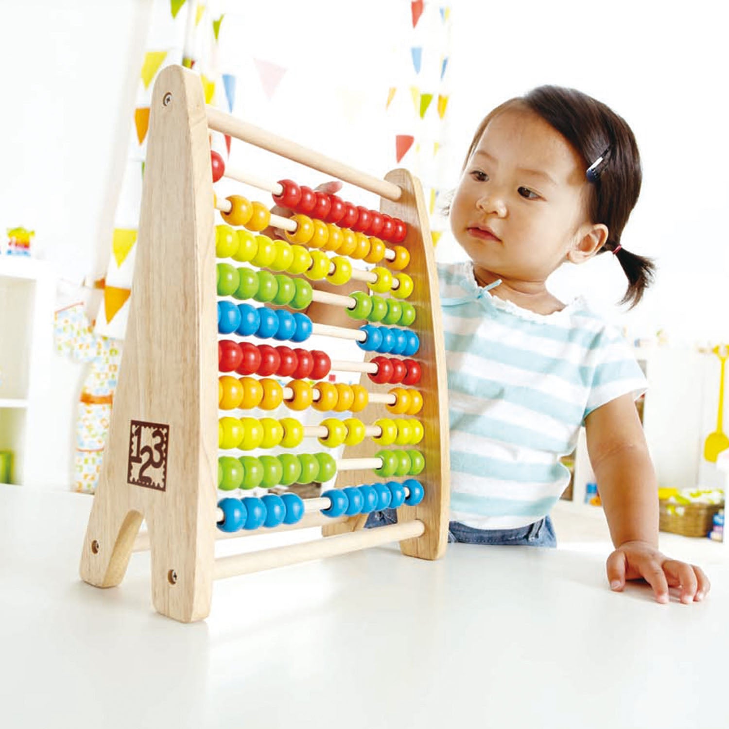 Menina brincando com o ábaco Hape de madeira, um brinquedo educativo para crianças a partir de 3 anos.