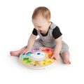 Bebé a brincar e interagir com o brinquedo musical Hape Baby Einstein Orquestra Magic Touch no chão.