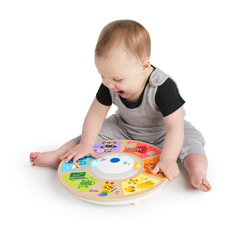 Bebé a brincar e interagir com o brinquedo musical Hape Baby Einstein Orquestra Magic Touch no chão.